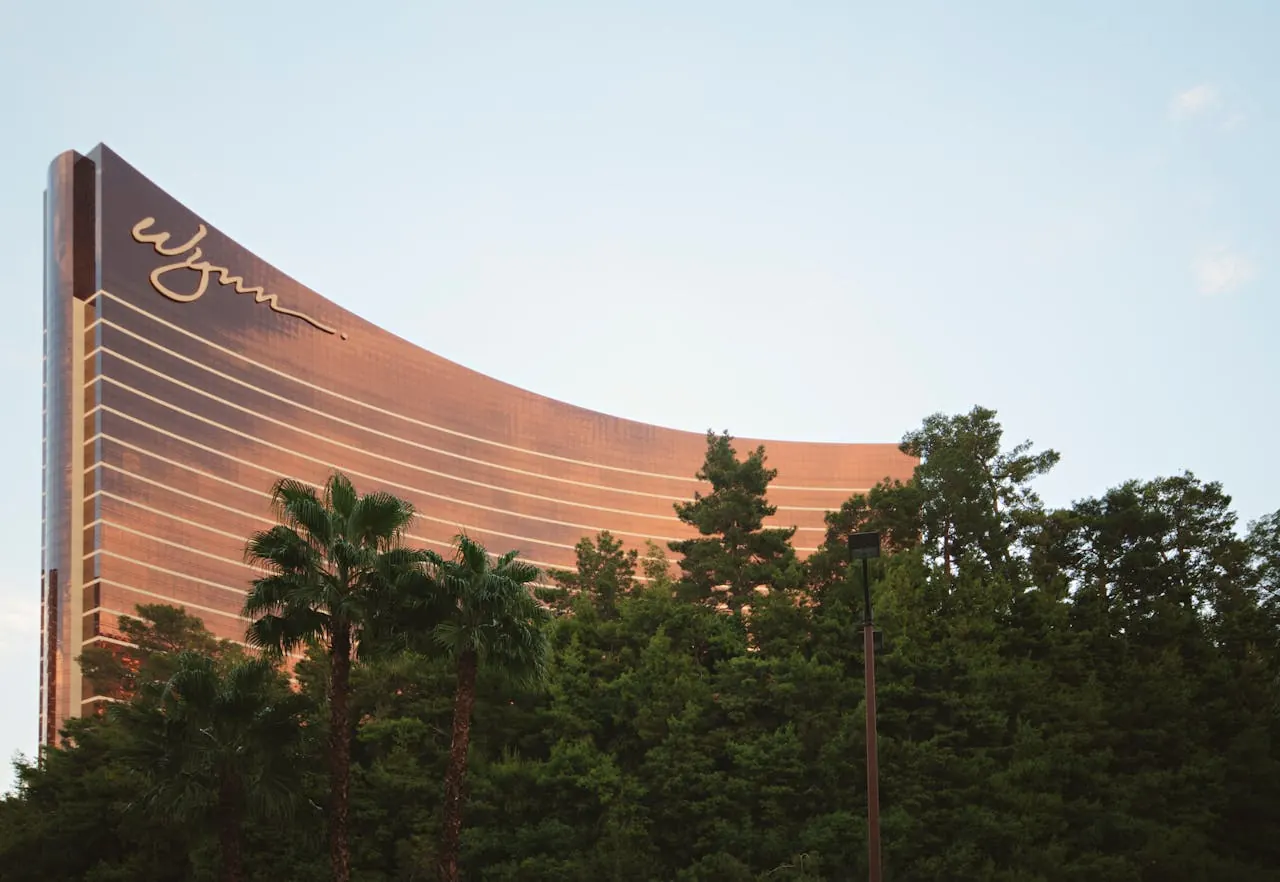 Curved casino resort tower rising above palm trees at dusk