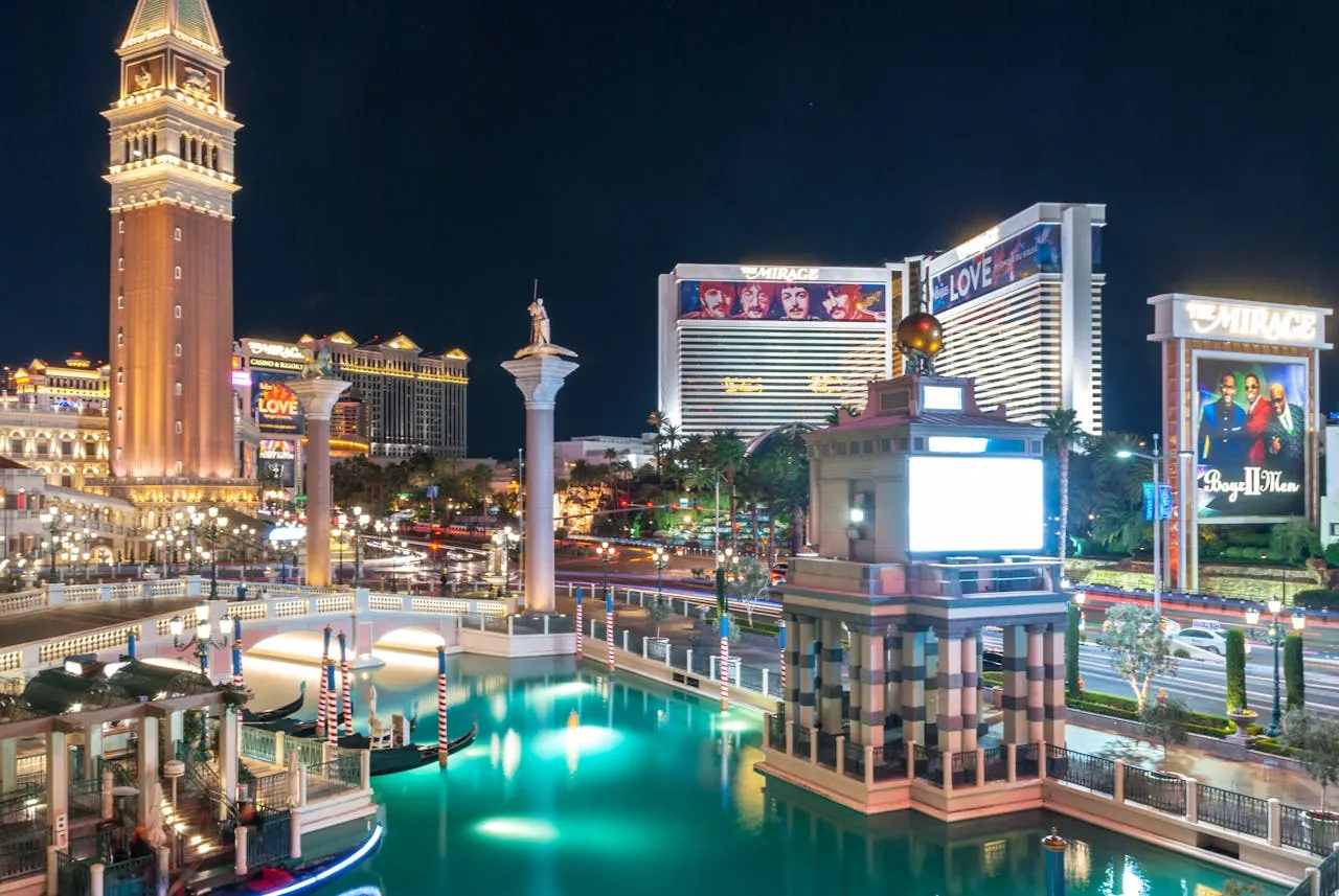 Casino resorts and a bell tower reflected in water after dark