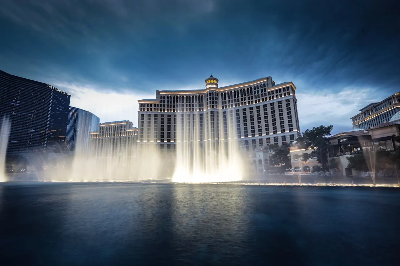 Illuminated fountains in front of a grand casino resort at dusk